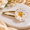 Elegant White Floral Hair Clip – Gold Finish Add a touch of elegance and charm to your hairstyle with this beautiful white floral hair clip. Featuring delicate translucent white petals with black speckled detailing, a shimmering golden